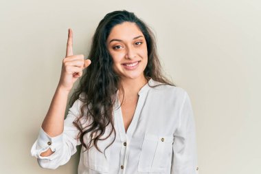 Gündelik kıyafetler giyen güzel bir ortadoğulu kadın başarılı bir fikirle işaret ediyor. Heyecanlı ve mutlu. Bir numara.. 