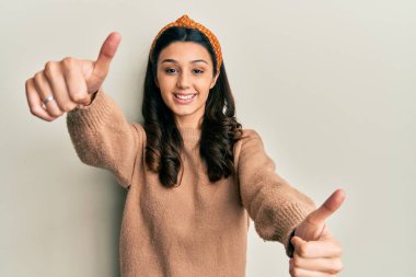 Latin kökenli genç bir kadın, günlük giysiler giyip, olumlu jestler yapıyor, gülümsüyor ve başarı için seviniyor. kazanan jest. 