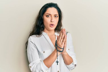 Güzel İspanyol bir kadın Katolik bir tespihle oynuyor. Şok olmuş suratıyla. Şüpheci ve alaycı görünüyor. 