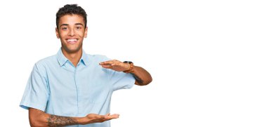 Genç, yakışıklı, Afro-Amerikalı sıradan kıyafetler giyen, elleri büyük ve büyük boy işareti gösteren, ölçü sembolü olan bir adam. Kameraya bakıp gülümsüyor. ölçüm kavramı. 