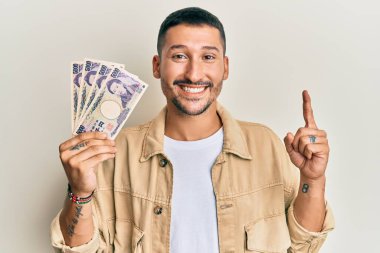 Elinde Japon yen banknotları olan yakışıklı bir adam bir fikir ya da soru işareti ile gülümsüyor ve gülümsüyor. 