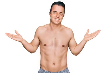 Mayo giyen yakışıklı genç adam gülümseyerek iki elini de açık tutuyor, sunuyor ve reklam karşılaştırması yapıyor ve dengeyi sağlıyor. 