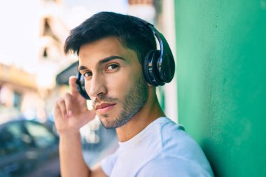 Şehirde kulaklık takan rahat yüzlü genç bir latin..