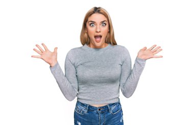 Gündelik giysiler giyen genç beyaz kadın zaferi mutlu bir gülümsemeyle kutluyor ve kazanan ifade ellerini kaldırarak ifade ediyor. 