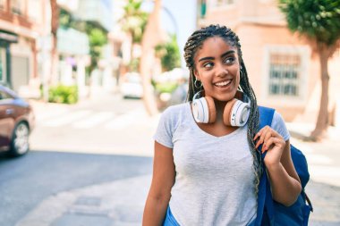 Genç Afrikalı Amerikalı öğrenci kampüste mutlu gülümsüyor.