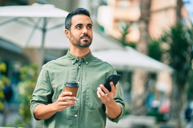 Şehirde akıllı telefon kullanan ciddi bir suratı olan genç bir İspanyol..