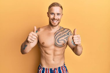 Yüzünde mayo olmayan beyaz bir adam elinde olumlu bir jest yapıyor, gülümsüyor ve başarı için seviniyor. kazanan jest. 