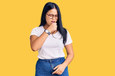 Genç ve güzel Asyalı kız günlük kıyafetler ve gözlük takıyor kendini iyi hissetmiyor ve soğuk algınlığı veya bronşitin belirtisi olarak öksürüyor. sağlık hizmeti kavramı. 