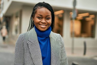 Genç Afrikalı Amerikalı iş kadını şehirde mutlu bir şekilde dikiliyor..