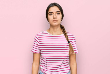 Günlük kıyafetler giyen genç İspanyol kadın yüzünde ciddi bir ifadeyle rahatlamış. Basit ve doğal bir şekilde kameraya bakıyorsun.. 