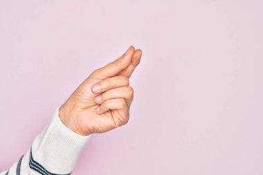 İzole edilmiş pembe arka planda parmaklarını gösteren beyaz bir gencin eli parmak, iş ve reklamla boş bir alan tutuyor.