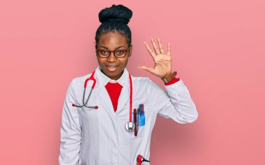 Genç Afro-Amerikan kadın doktor üniforması ve steteskop giyiyor. Beş numarayı gösterip işaret ederken kendinden emin ve mutlu gülümsüyor.. 