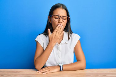 Güzel İspanyol kadın, gündelik giysiler içinde masada oturuyor. Ağzı eliyle kapatmaktan sıkılmış. Huzursuz ve uykulu.. 