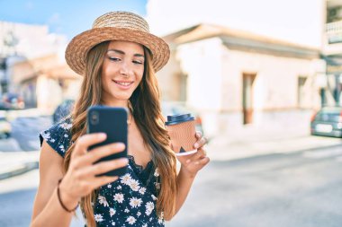 Genç İspanyol kadın tatilde. Akıllı telefonun yanında selfie çekiyor. Şehir caddesinde kahve içiyor..