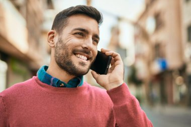 Genç İspanyol adam gülümsüyor. Şehirdeki akıllı telefondan konuşuyor..