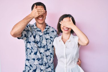 Gündelik giysiler giyen, gülümseyen ve gülümseyen güzel bir çift şaşırtmak için gözlerini kapatıyor. kör kavram. 