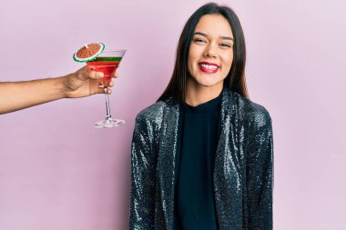 Seksi parti ceketi giyen ve İspanyol kolu olan genç bir kız mutlu ve havalı bir gülümsemeyle kokteyl sunuyor. şanslı kişi. 