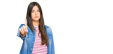 Genç esmer kadın, gündelik giysiler giyip parmağını kaldırmış ve kızgın bir ifade takınıyor. 