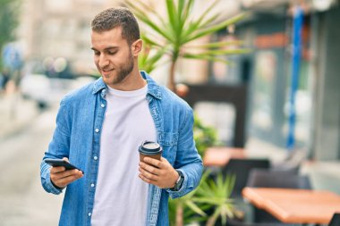 Kafkasyalı genç adam akıllı telefon kullanıyor. Şehirde kahve içiyor..