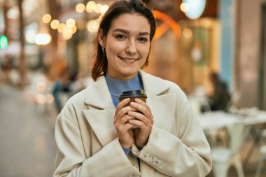 Genç İspanyol kadın gülümsüyor. Mutlu bir şekilde içiyor. Şehirde kahve içiyor.