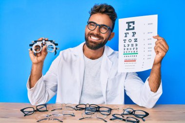 Optometri gözlüklü ve yüzünde mutlu ve havalı bir gülümsemeyle gülümseyen mektupları olan İspanyol genç bir adam. diş gösterme. 