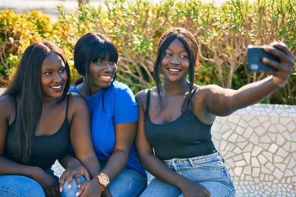 Three african american friends smiling happy making selfie by the smartphone at the park.