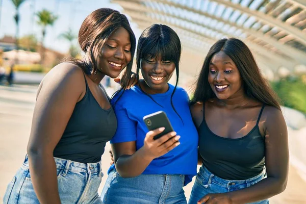 3人のアフリカ系アメリカ人の友人が市内のスマートフォンを使って笑顔で — ストック写真