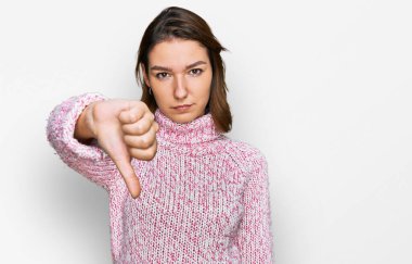 Kışlık yün kazak giyen genç beyaz kız mutsuz ve kızgın görünüyor. Reddedilmiş ve olumsuz. kötü ifade. 