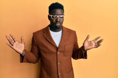 Zarif kıyafetler ve gözlük takan yakışıklı siyahi adam habersiz ve kolları açık, hiçbir fikrim yok ve şüpheli bir yüzüm var.. 