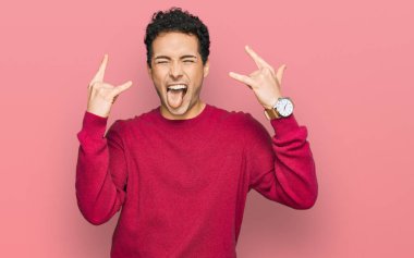 Genç, yakışıklı, günlük kıyafetler giymiş, çılgın bir ifadeyle bağıran, elleri havada rock sembolü yapan bir adam. Müzik yıldızı. ağır müzik konsepti. 