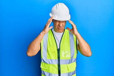 Orta yaşlı kel bir adam, mimar şapkası takıyor, eli başının üstünde, stres yüzünden başı ağrıyor. migren ağrısı. 