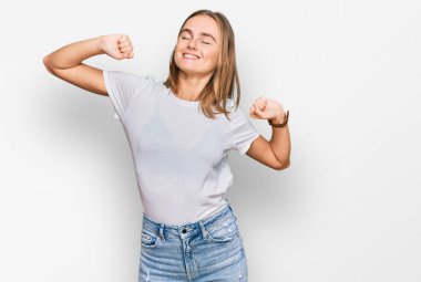 Güzel, genç, sarışın bir kadın, gündelik beyaz tişörtler giyiyor. Yorgun ve rahat, uykulu ve sabahın erken saatleri için esniyor. 