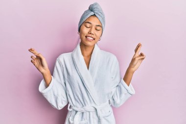 Duş havlusu şapkası ve bornoz takan genç Çinli kadın umut ve gözlerin kapalı bir şekilde gülümseyerek işaret ediyor. Şans ve batıl inançlar. 