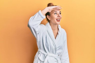 Bornoz giyen genç sarışın kadın çok mutlu ve gülümsüyor. arama kavramı. 