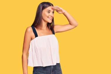 Genç İspanyol kadın gündelik giysiler giyiyor çok mutlu ve gülümsüyor başlarını kaldırıp uzaklara bakıyor. arama kavramı. 