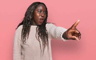 Kışın yün kazak giyen genç Afrikalı bir kadın parmağıyla işaret ederek şaşırdı, ağzı açık hayrete düştü, ön tarafta bir şey vardı. 