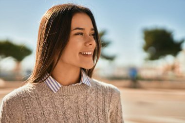 Genç İspanyol kız gülümseyerek şehirde mutlu mesut dikiliyor..