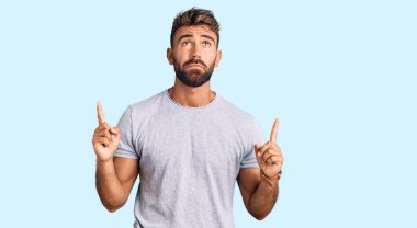 Gündelik kıyafetler giyen genç İspanyol adam üzgün ve üzgün görünüyor, parmaklarıyla yön gösteriyor, mutsuz ve depresif.. 