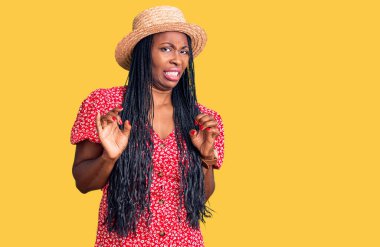 Yazlık şapkalı genç Afro-Amerikan kadın tiksindirici bir ifade takınıyor ve tiksindirici bir yüz ifadesi takınıyor.. 
