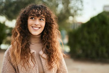 Genç İspanyol kadın gülümseyerek şehirde mutlu mesut dikiliyor.