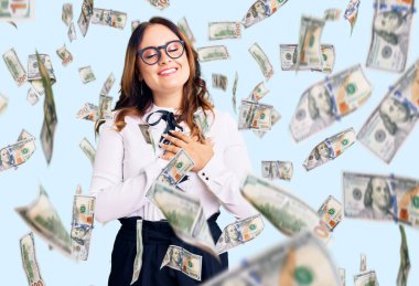 İş gömleği ve gözlük takan, elleri göğsünde, gözleri kapalı gülümseyen ve yüzünde minnet ifadesi olan güzel beyaz bir kadın. sağlık kavramı.