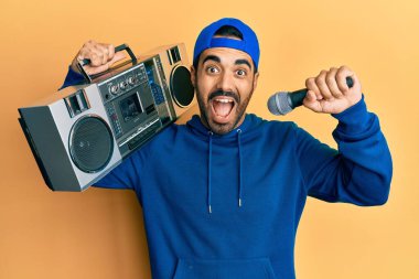 Kasetçalar tutan genç İspanyol adam, mikrofonla şarkı dinlerken çılgın kutlamalar yapıyor ve başarı için hayrete düşmüş gözleri açık heyecanlı çığlıklar atıyor.. 