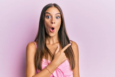 Kolsuz tişörtlü, gündelik giyinen genç İspanyol kadın parmaklarını yana çevirerek şaşırdı, ağzı açık şaşkın bir ifade takındı.. 