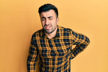 Sırt ağrısı çeken, sırt ağrısı çeken, elle dokunan, sıradan kıyafetler giyen İspanyol genç bir adam. 