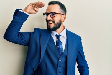 Sakallı, takım elbiseli, kravatlı, mutlu ve tebessüm eden genç bir adam. arama kavramı. 