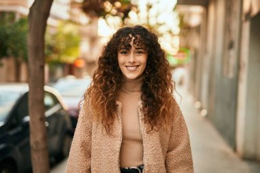 Genç İspanyol kadın gülümseyerek şehirde mutlu mesut dikiliyor.