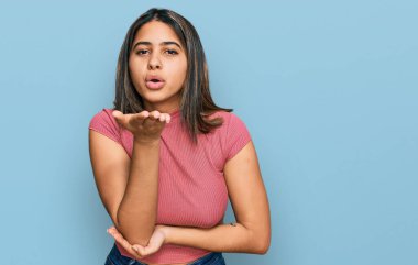 Gündelik tişört giyen genç İspanyol kız kameraya bakıp havada bir öpücük savuruyor ve güzel ve seksi oluyor. aşk ifadesi. 