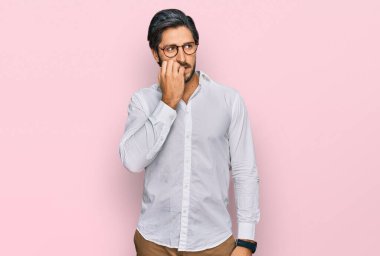 İş gömleği giyen, gözlüklü, stresli ve gergin görünen ağzı tırnak yiyen genç bir İspanyol. anksiyete. 