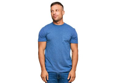 Yakışıklı, kaslı, günlük kıyafetler giyen, gülümseyen, yan tarafa bakıp düşünen bir adam.. 