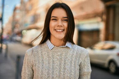 Genç İspanyol kız gülümseyerek şehirde mutlu mesut dikiliyor..